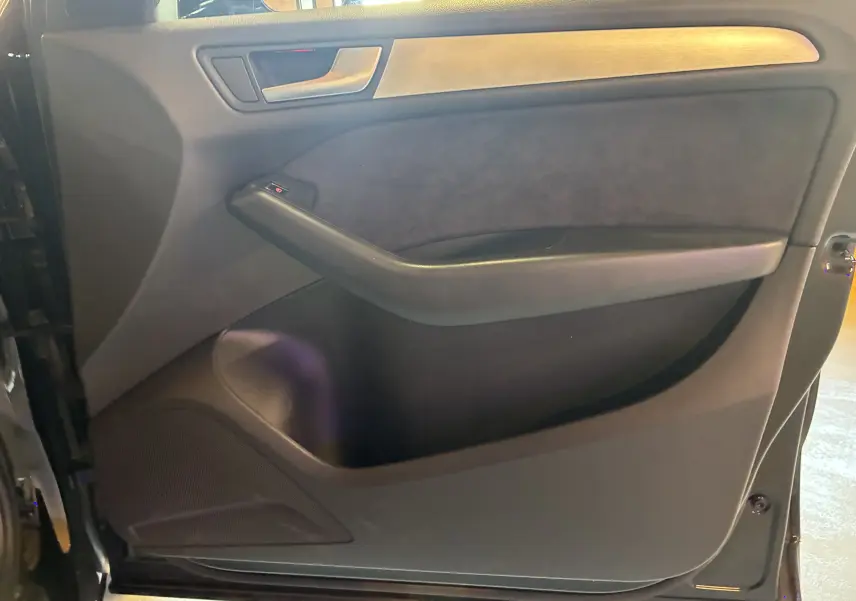 Vue intérieure côté gauche de la porte avant noire de l'Audi SQ5 avec insert décoratif métal et commande de vitre.