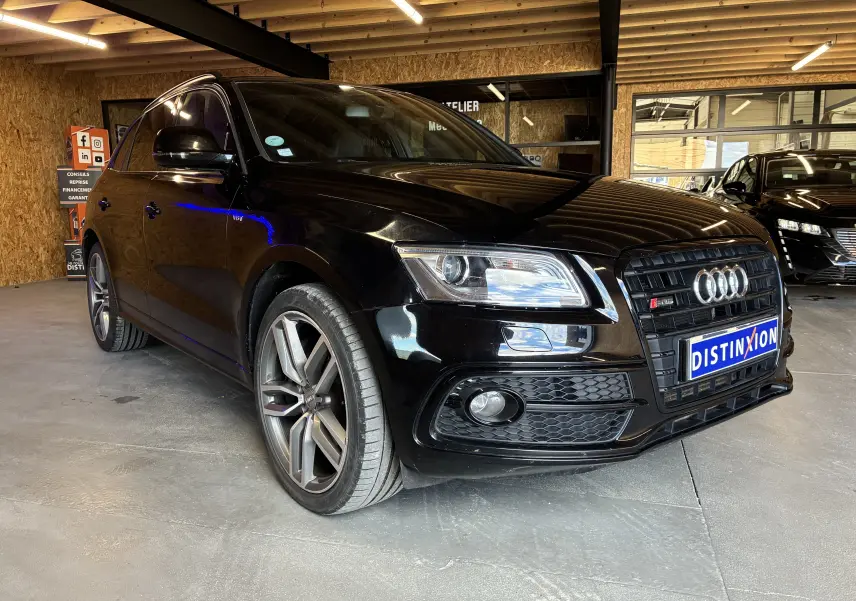 Audi SQ5 noir vue 3/4 avant droit en intérieur, avec jantes alu et calandre noire distinctive.