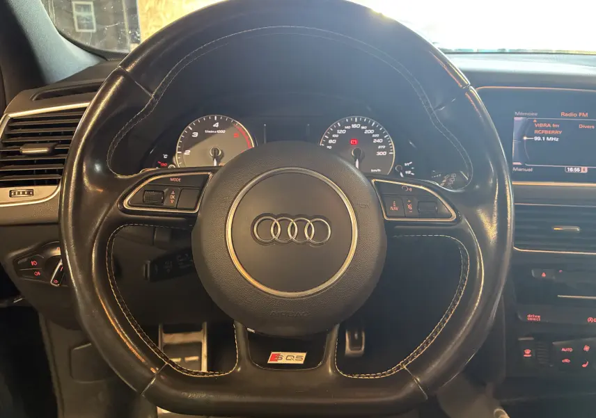 Vue rapprochée du volant cuir noir multifonctions d’Audi SQ5 avec logo S Q5 et tableau de bord visible en arrière-plan.