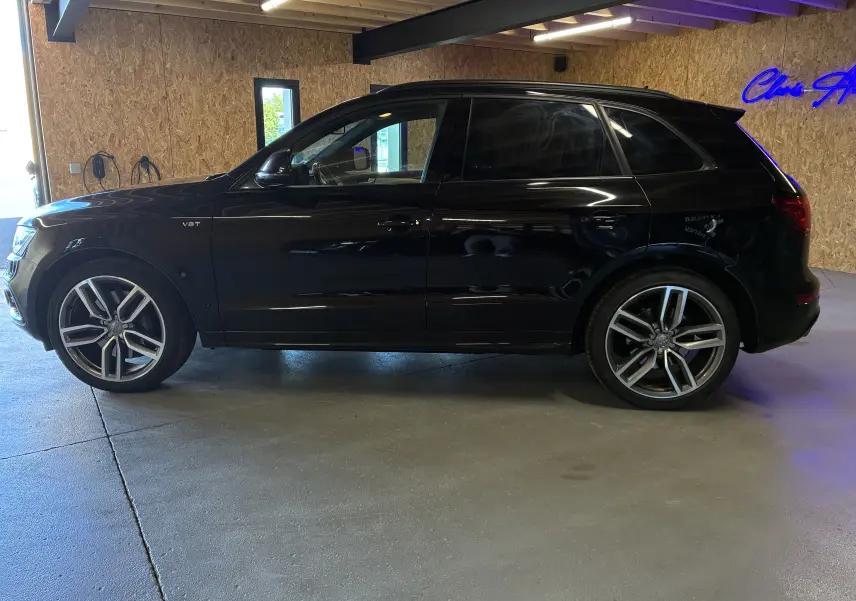 Audi SQ5 noir en vue de profil côté gauche, avec jantes alu et vitres arrière surteintées dans un garage.