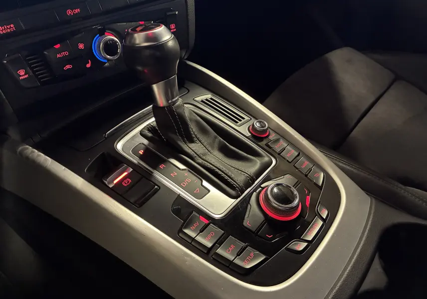 Vue rapprochée de la console centrale noire de l'Audi SQ5 2016, avec levier de vitesses automatique et commandes rétroéclairées rouges.