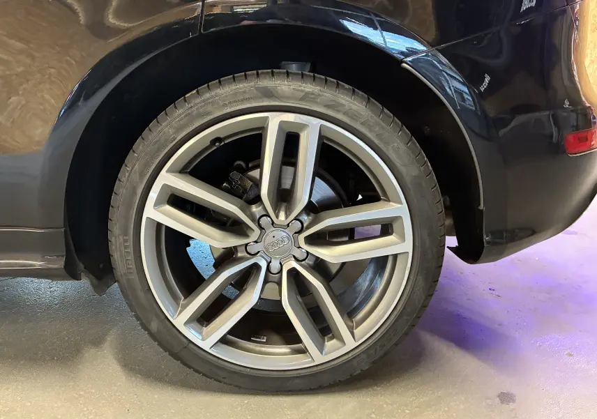 Gros plan sur la roue arrière droite d'une Audi SQ5 noire, avec jante alu à design moderne et pneu Pirelli.