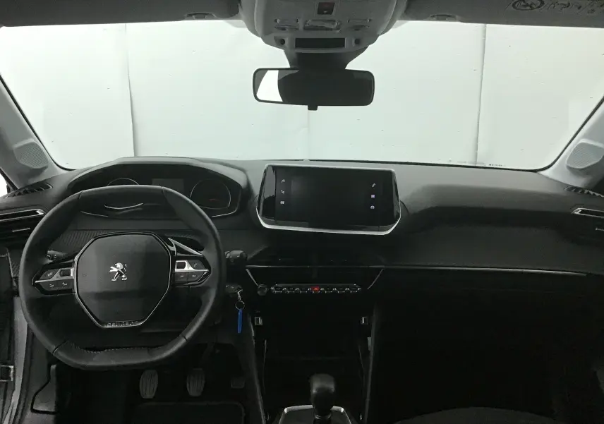Intérieur de la Peugeot 208 2022 vue de face, tableau de bord noir avec écran tactile central et volant compact griffé Peugeot.