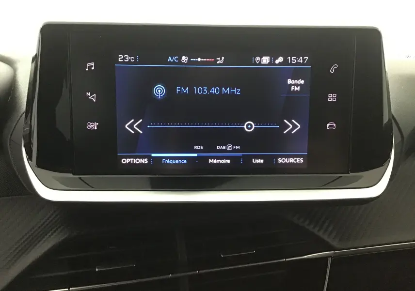 Écran tactile central du tableau de bord du Peugeot 208 1.2 PureTech 100 Style Gris Artense affichant la radio FM.