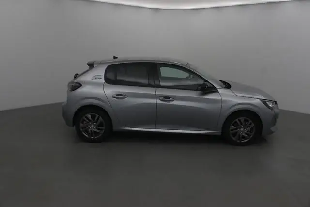 Profil côté gauche d'une Peugeot 208 gris Artense 2022 avec jantes alliage et vitres teintées dans un studio neutre.