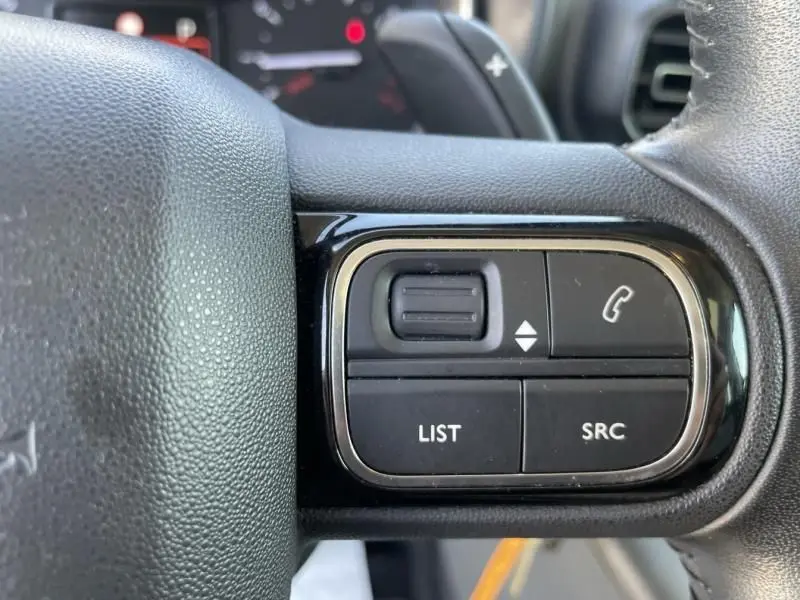 Gros plan sur les commandes noires du volant du Citroën Berlingo gris métal 2018, avec boutons list, source et appel.