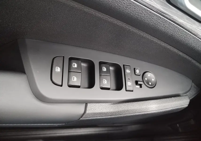 Gros plan sur la commande des vitres et rétroviseurs côté conducteur du Kia Sportage gris perle 2025.