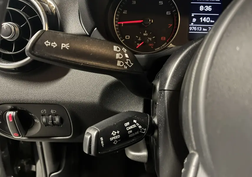 Gros plan sur la commande de clignotants et régulateur de vitesse dans l’habitacle gris-noir d’une Audi A1 2016.