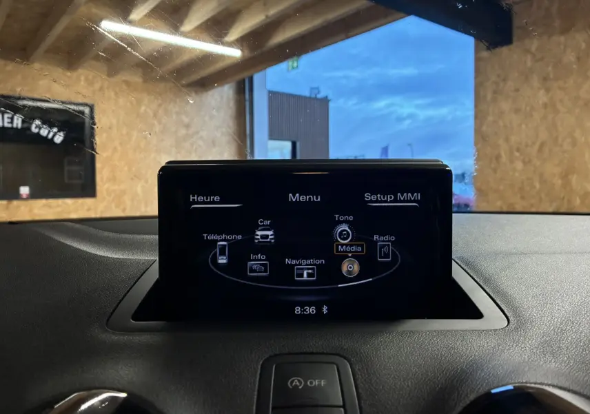 Écran central du système MMI de l'Audi A1 noir 2016, affichant le menu multimédia dans un intérieur sombre.