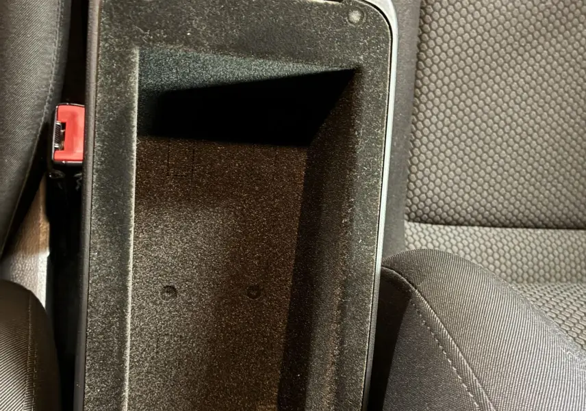 Vue plongeante sur le rangement central ouvert entre les sièges en tissu gris foncé de l'Audi A1 1.0 TFSI S-Line noire de 2016.