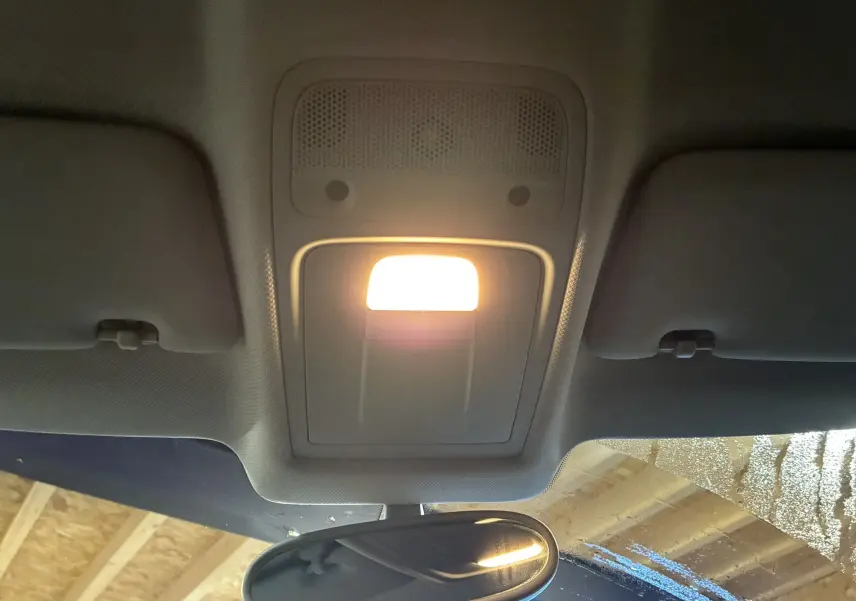 Vue intérieure centrée sur le plafonnier allumé et le rétroviseur intérieur d’une Audi A1 noire de 2016.
