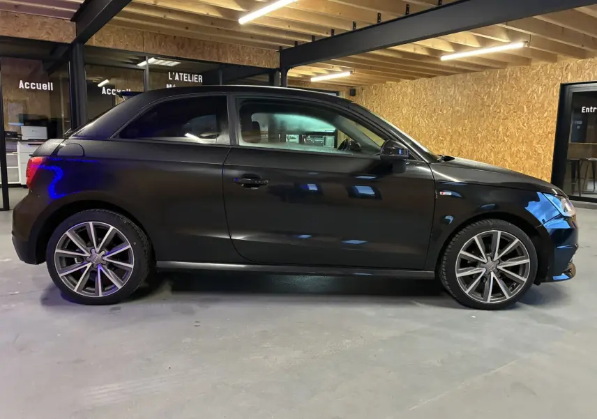 Audi A1 noir vue de profil côté gauche, avec jantes alliage 17 pouces et finition S-Line visible sur l'aile avant.