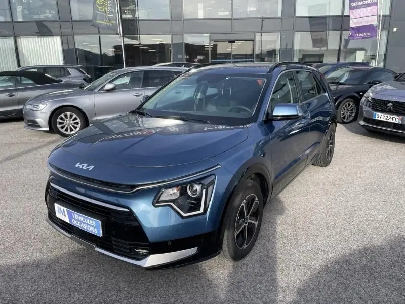 KIA Niro 2024 bleu métal en vue 3/4 avant droit, avec signature lumineuse distinctive et jantes noires.