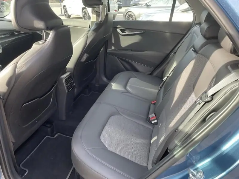 Vue intérieure arrière côté gauche du Kia Niro 2024 bleu métal, montrant les sièges en cuir et tissu gris avec ceinture de sécurité.