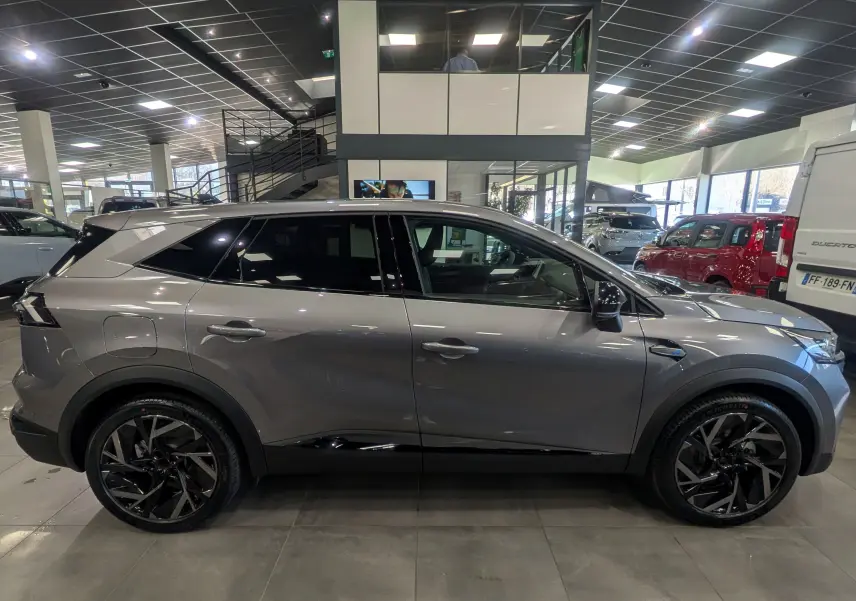 Vue de profil droit du Renault SYMBIOZ E-TECH gris Cassiopé, avec jantes noires et toit noir en concession.