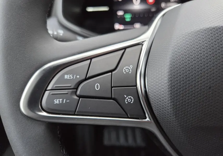 Gros plan sur les commandes de régulateur de vitesse au volant de la Renault Clio 2025, finition noire avec contours chromés.