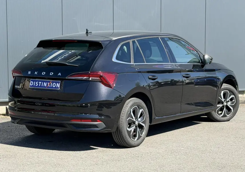 Vue 3/4 arrière droite d'une Skoda Scala noire Magic Perle avec jantes alliage et vitres surteintées.