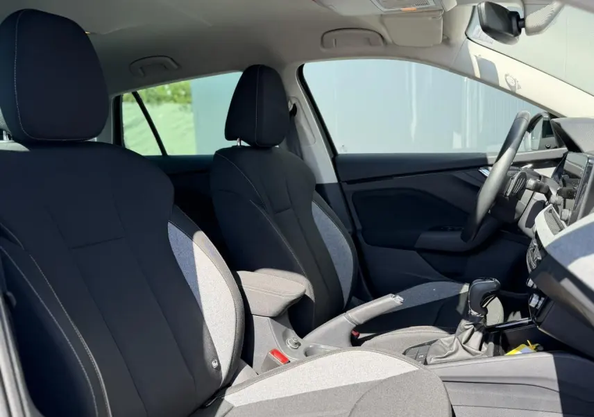 Intérieur avant de la Skoda Scala 2025, vue côté droit, sièges bi-ton gris et noir avec accoudoir central.