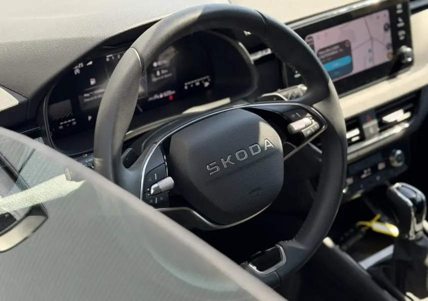 Vue rapprochée du volant noir multifonctions SKODA dans l’habitacle avec tableau de bord digital et écran tactile.
