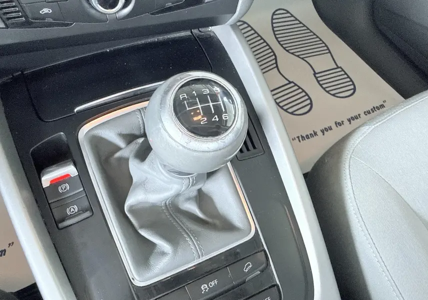 Gros plan sur le levier de vitesses manuel gris de l'Audi Q5, entouré de la console centrale noire et grise.