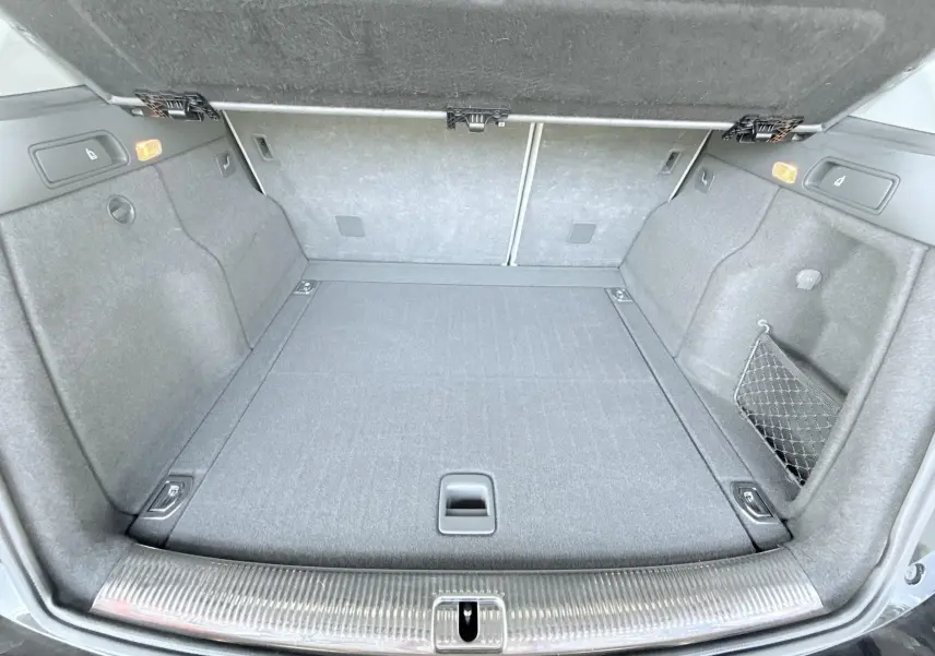 Coffre ouvert vu de l'arrière d'un Audi Q5 noir, montrant un espace de chargement propre et bien agencé.