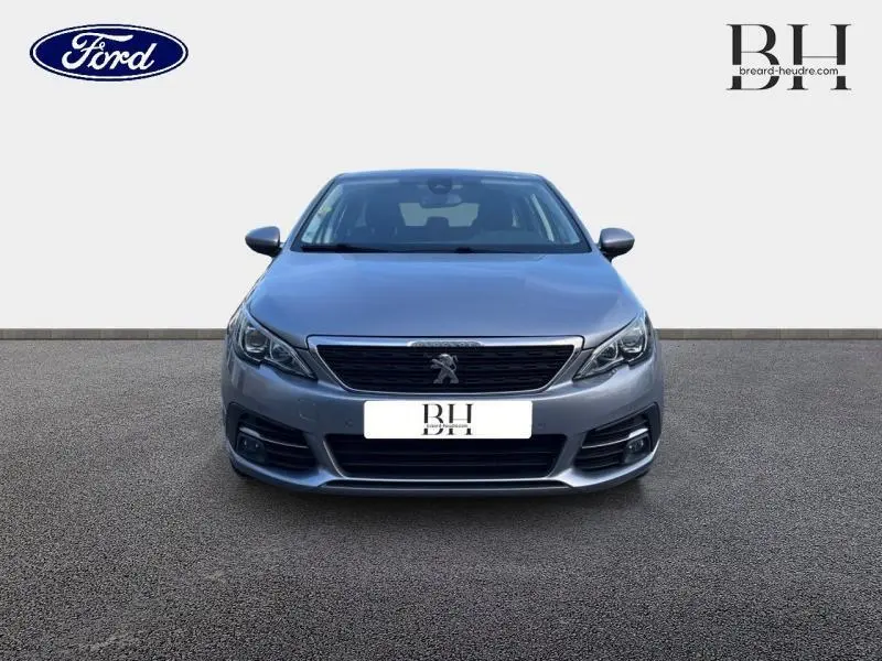 Vue frontale d'une Peugeot 308 SW 2021 gris Artense avec calandre noire et logo lion central visible.