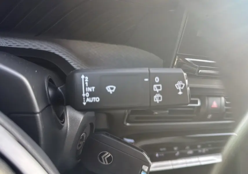 Gros plan sur la commande d’essuie-glace à gauche du volant dans l’habitacle du Citroën C3 Aircross noir perla nera 2025.