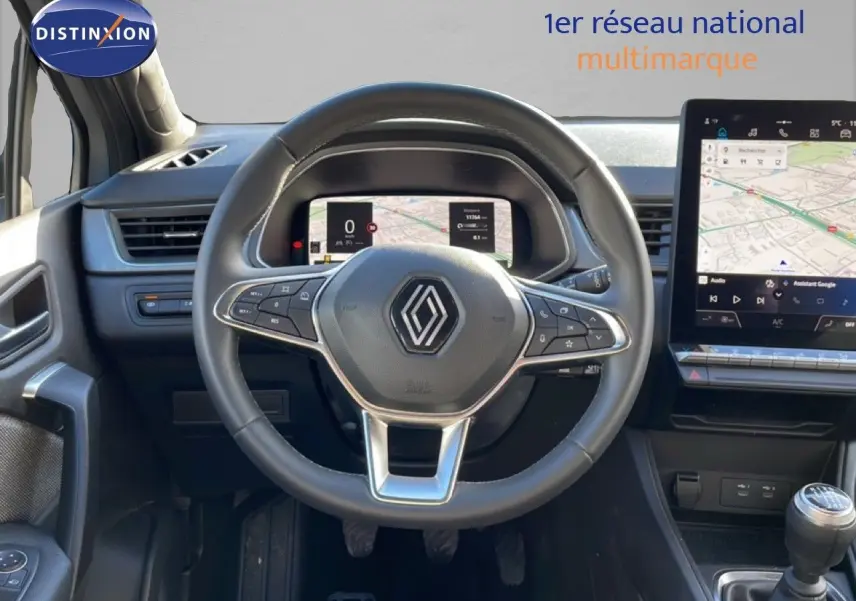 Vue intérieure centrée sur le volant et tableau de bord numérique du Renault Captur gris Rafale avec écran tactile et boîte manuelle.
