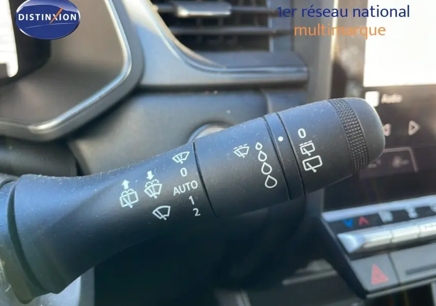 Gros plan sur la commande d’essuie-glace du Renault Captur gris, avec tableau de bord et écran tactile en arrière-plan.