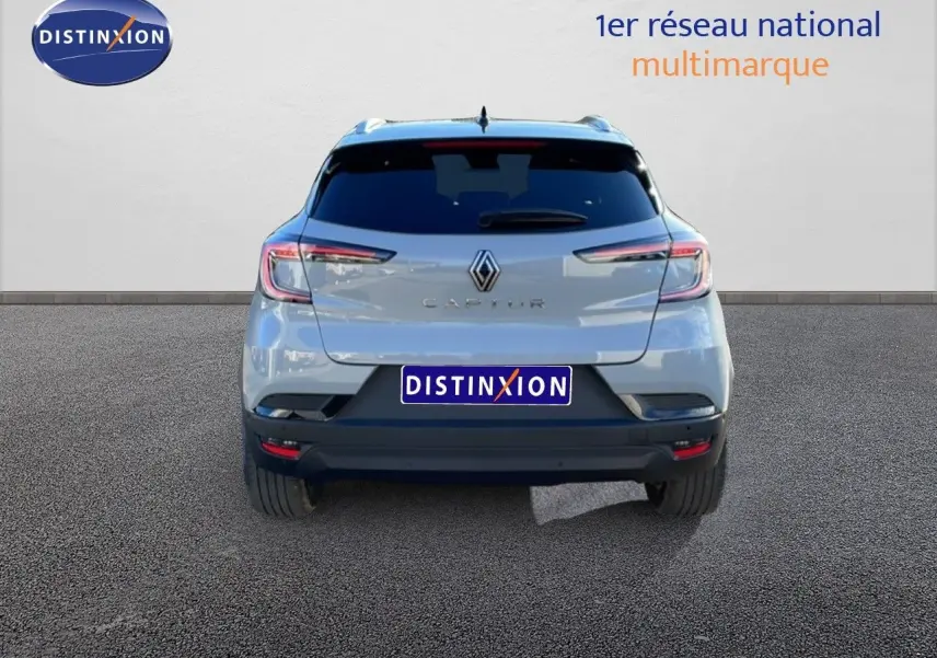 Vue arrière d'un Renault Captur gris Rafale métallisé avec toit noir, sur fond neutre avec logo Distinxion.
