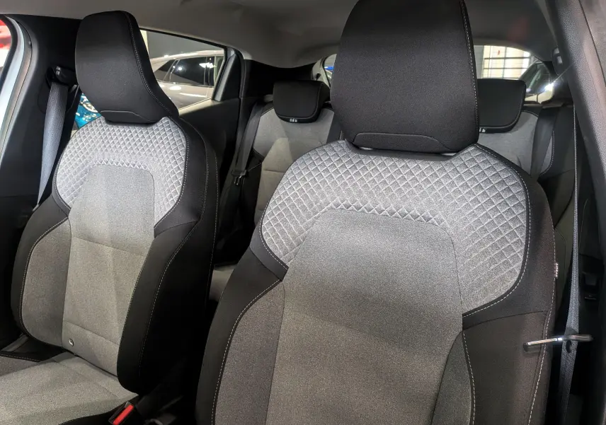 Gros plan sur les sièges avant en tissu gris et noir de la Renault Clio V Blanc Glacier, intérieur moderne et soigné.