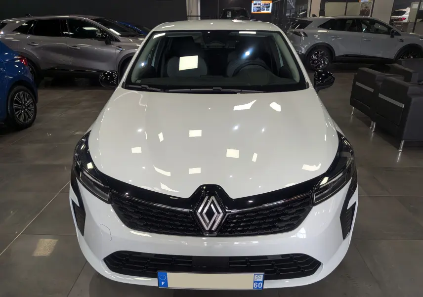 Vue avant d'une Renault Clio V Blanc Glacier en showroom, avec calandre noire et logo Renault bien visible.