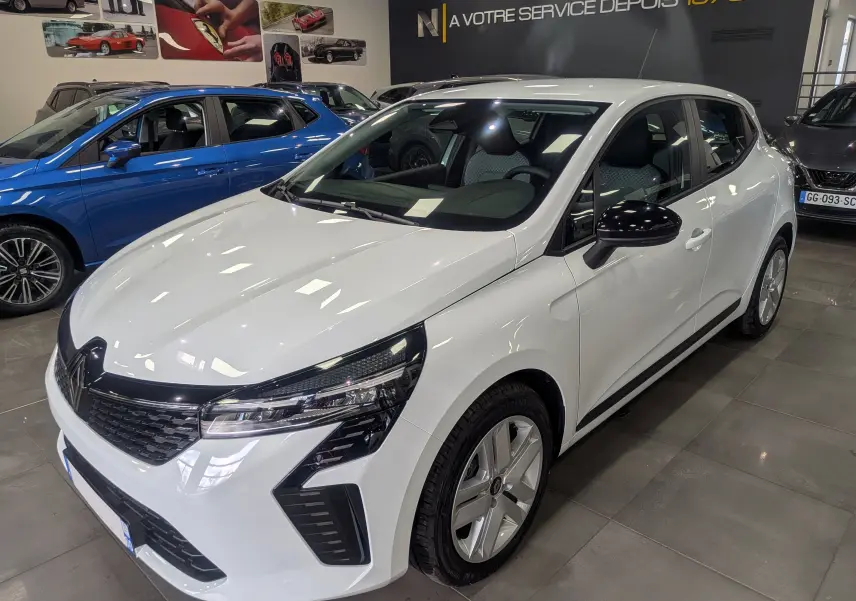 Renault Clio V Blue dCi 100 Evolution blanc glacier vue 3/4 avant droit en intérieur avec détails noirs contrastants.