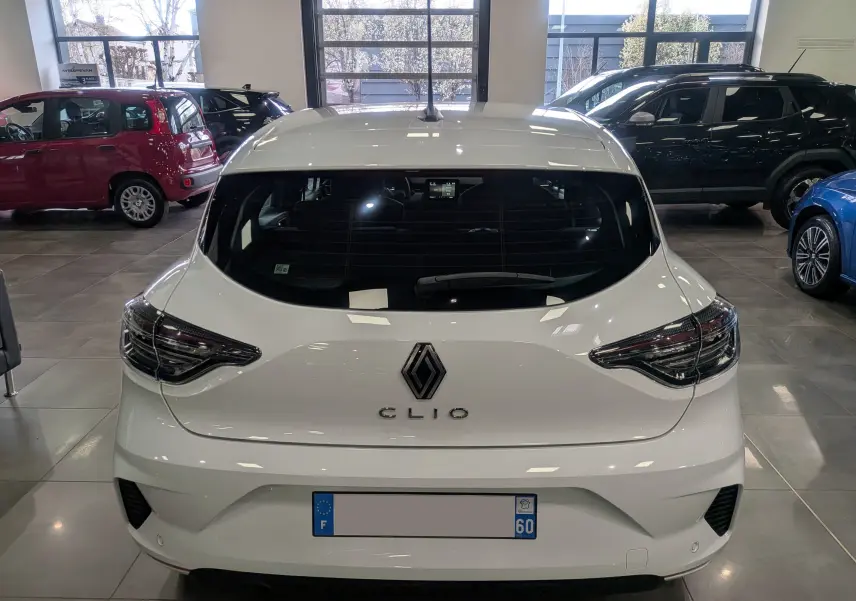 Vue arrière d'une Renault Clio V Blanc Glacier 2025 en showroom, avec feux arrière LED et logo Renault bien visibles.