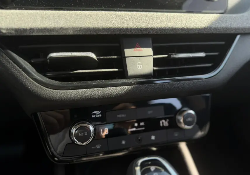 Gros plan sur la console centrale noire brillante de la Skoda Scala TSI 116 DSG7 avec commandes climatisation automatique.