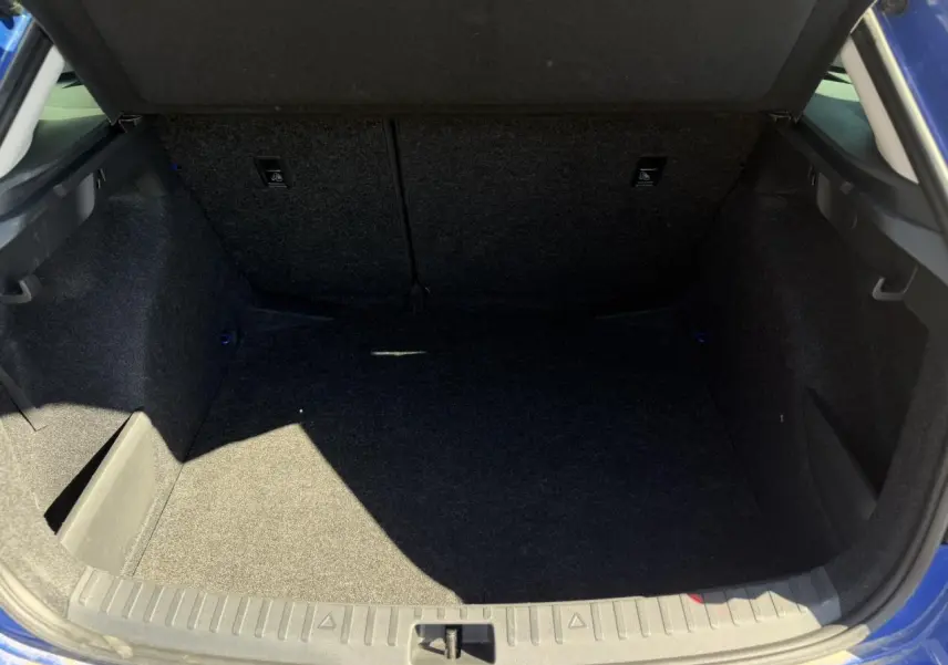 Coffre ouvert vu de l'arrière d'une Skoda Scala TSI 116 DSG7 bleu Energy, espace de chargement vide et propre.