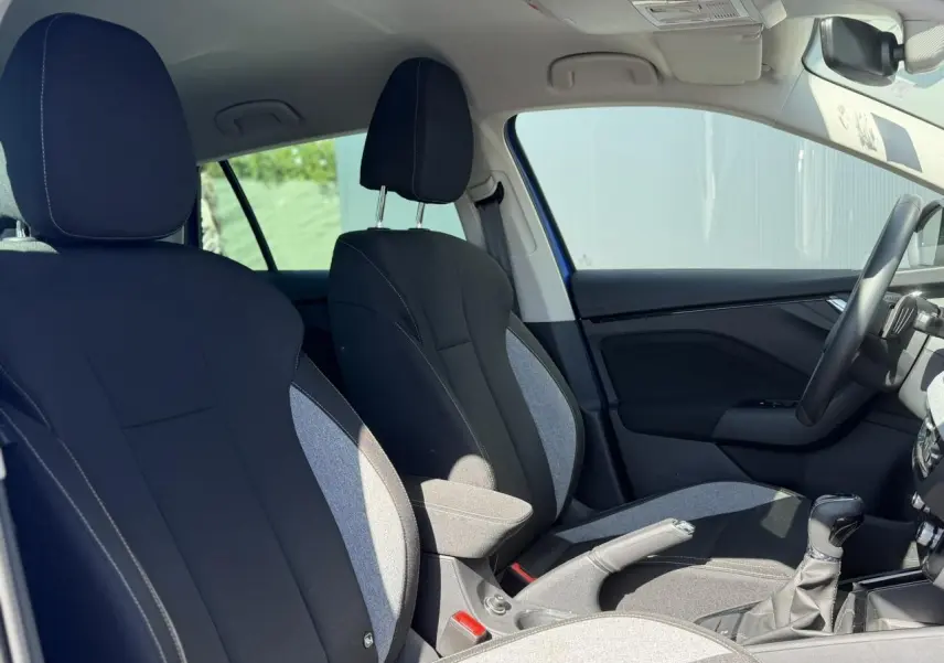 Vue intérieure côté droit de la Skoda Scala 2025 bleu Energy, sièges tissu bicolore avec accoudoir central et volant multifonctions.