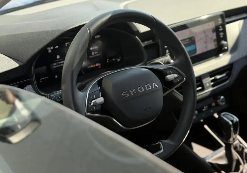 Vue rapprochée du volant en cuir noir marqué SKODA et du tableau de bord numérique de la Skoda Scala 2025.