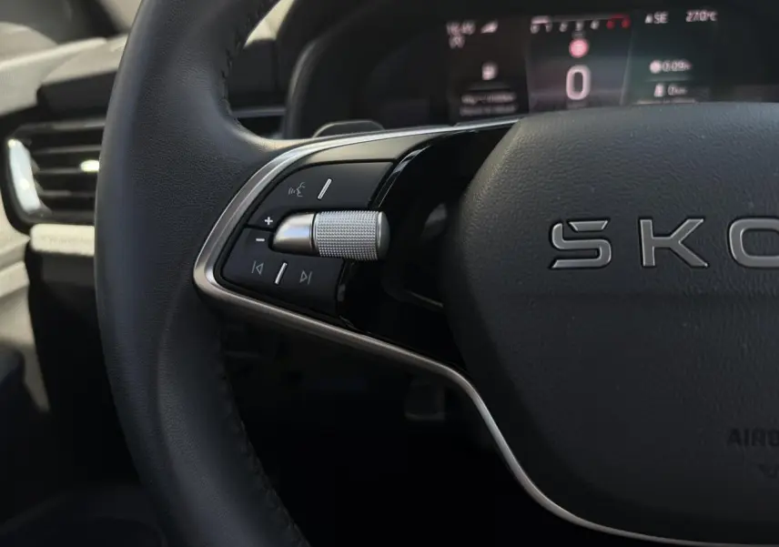 Gros plan sur le volant cuir noir de la Skoda Scala 2025 avec commandes multifonctions et tableau de bord numérique flou.