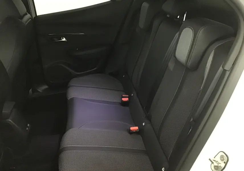 Vue du siège arrière côté droit du Peugeot 2008 blanc nacré, montrant les assises en tissu noir et détails de la portière.