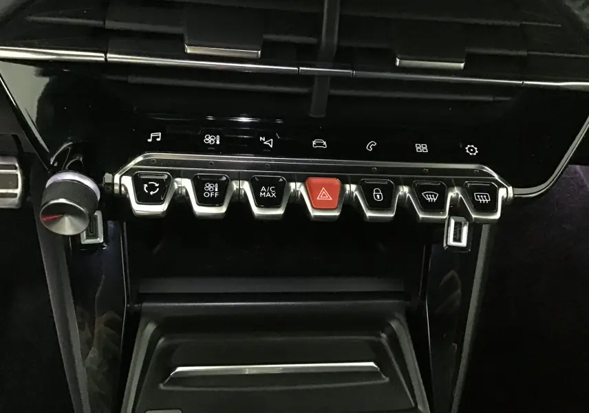 Gros plan sur la console centrale du Peugeot 2008 GT 2021, montrant les commandes climatisation et bouton hazard rouge.