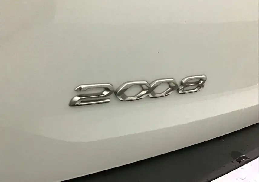 Gros plan sur l'arrière blanc nacré du Peugeot 2008 2021, mettant en valeur l'emblème chromé du modèle.
