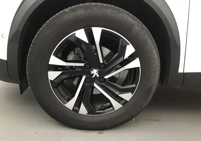 Gros plan sur la jante alliage noire et argentée du côté gauche d'un Peugeot 2008 blanc nacré.