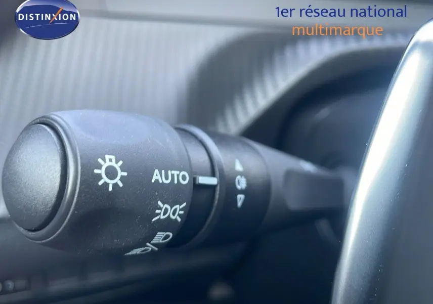 Gros plan sur la commande des phares du Peugeot 2008 gris Artense, côté gauche du volant, intérieur moderne.