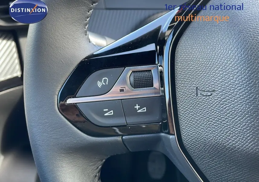 Gros plan sur les commandes gauche du volant du Peugeot 2008 rouge Elixir Metal, mettant en valeur les boutons de réglage audio.