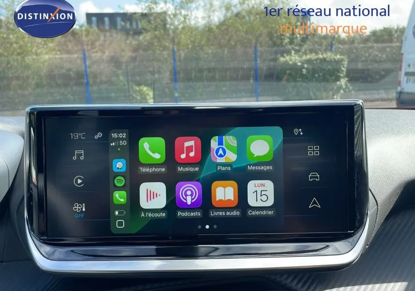 Écran tactile central du Peugeot 2008 2025 affichant les applications connectées, avec tableau de bord en arrière-plan.