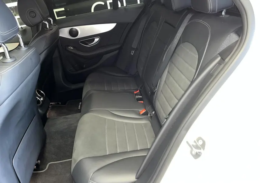 Vue côté droit de l'habitacle arrière du break Mercedes Classe C blanc, sièges en cuir noir et alcantara avec surpiqûres grises.