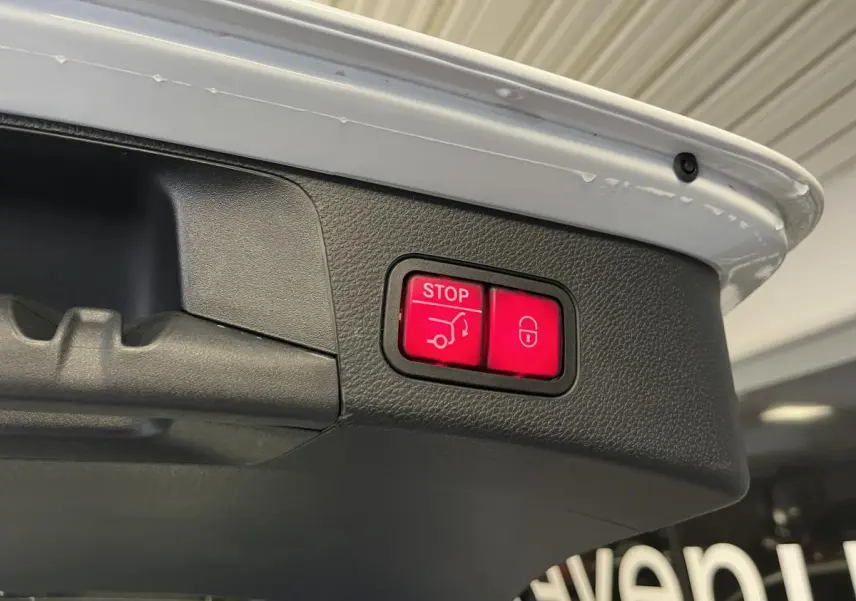 Boutons rouges de fermeture électrique du hayon sur le coffre d'un break Mercedes Classe C blanc.