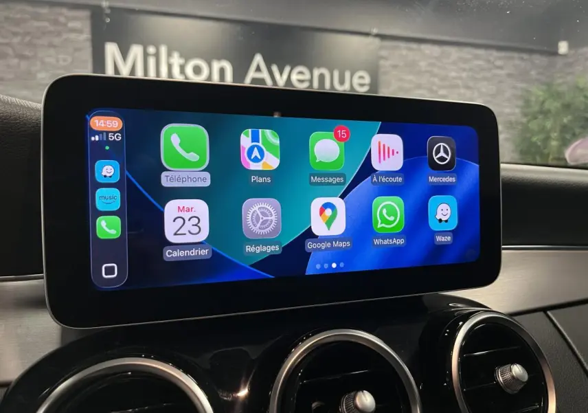 Écran tactile central affichant l’intégration smartphone dans le tableau de bord noir d’un Mercedes Classe C Break blanc.