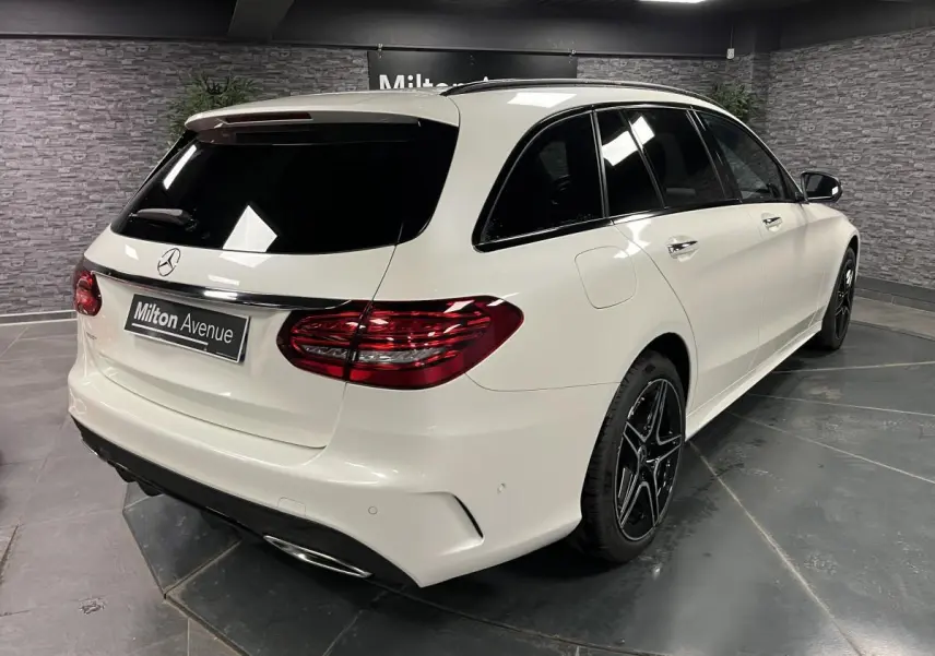 Mercedes Classe C Break blanc en 3/4 arrière droit avec jantes AMG noires et vitres teintées.